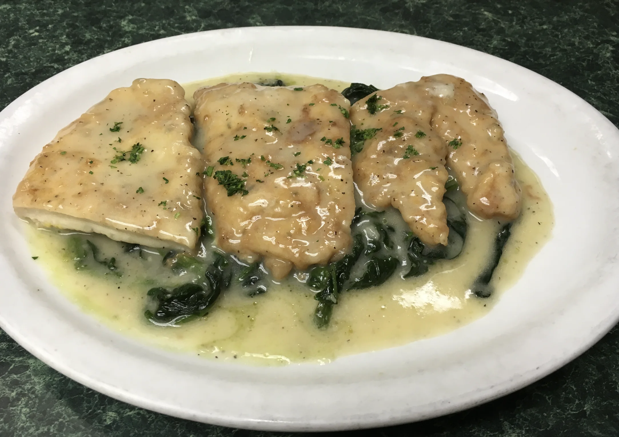 Chicken served in a light sauce over sautéed spinach