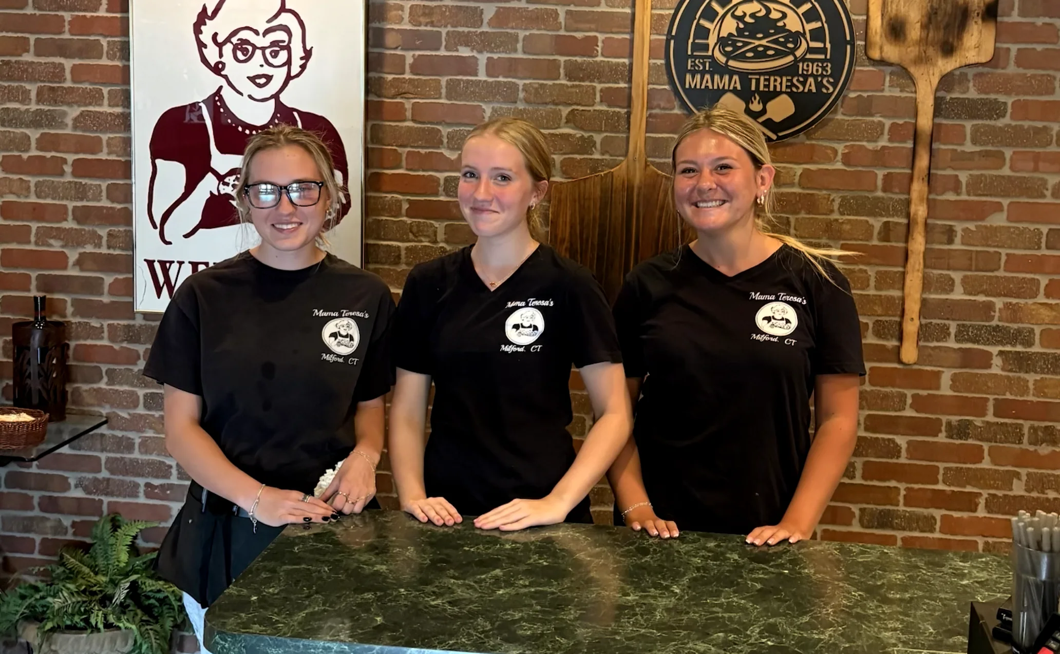 The Mama Teresa's team smiling behind the restaurant counter
